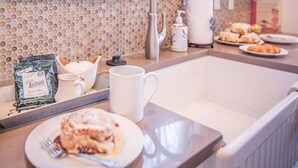 A kitchen with a modern sink, a tray with a coffee mug, a plate with food, and a decorative plant on the window sill. - Beautiful Branson Home! Perfect Downtown Location! (Branson)