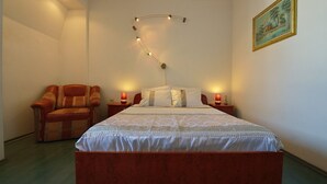 Een slaapkamer met een groot bed, twee nachtkastjes met lampen, een stoel en een schilderij aan de muur.