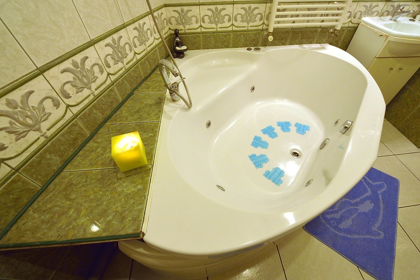 A bathroom with a freestanding bathtub, a yellow candle, and a blue bath mat.