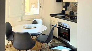 Et kompakt køkken med hvide skabe, en sort bordplade og en moderne komfur.