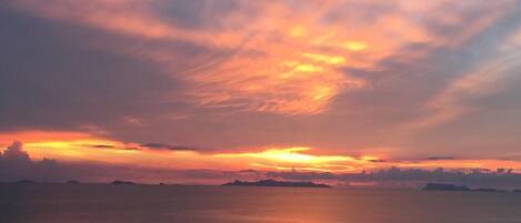 Ein Sonnenuntergang über einem ruhigen Meer mit einer an das Wasser reichenden Seebrücke.