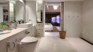 A modern bathroom with a large mirror, a white sink, and a toilet. There is a glass shelf above the sink and a wicker basket on the floor. - The Headland Villa 2, stunning beachfront, Samui (Koh Samui)