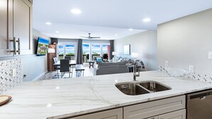 A modern kitchen with a marble countertop, stainless steel sink, and built-in appliances. - Beachfront Boutique Resort  |  Coastal Retreat  |  Casa Condo 203 (Port Aransas)