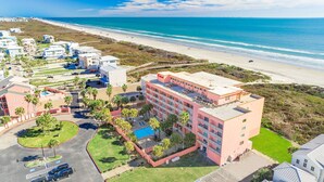 Un hotel costero con varios pisos, una piscina y vista al mar.