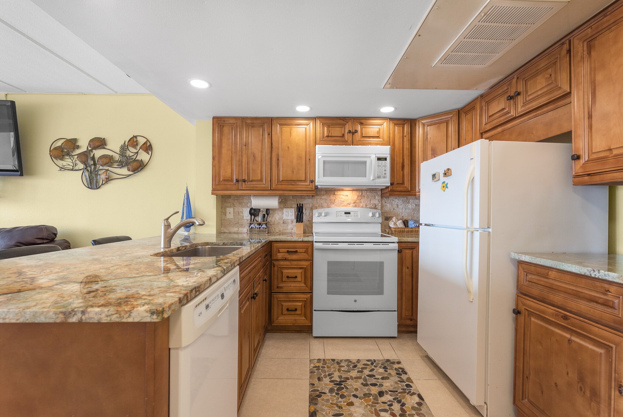 A kitchen with wooden cabinets, a white stove, a microwave, and a refrigerator.