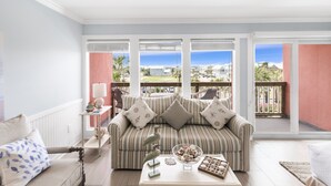 Ein Wohnzimmer mit einem gestreiften Sofa, einem Couchtisch mit Dekoration und Blick ins Freie.