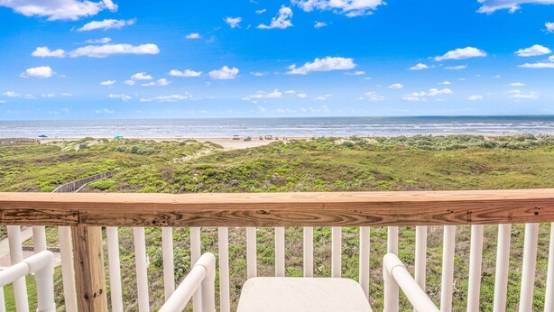A wooden deck with white railings overlooking a beach with a clear sky. - Beachfront Boutique Resort | Sunset Serentity | Casa Condo 402 (Port Aransas)