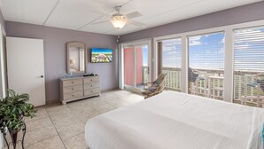 A bedroom with a bed, a dresser, a mirror, and a ceiling fan. - Beachfront Boutique Resort | Sunset Serentity | Casa Condo 402 (Port Aransas)