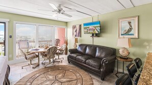 A living room with a brown leather couch, a round coffee table, and a ceiling fan. - Beachfront Boutique Resort | Seaside Haven | Casa Condo 406 (Port Aransas)