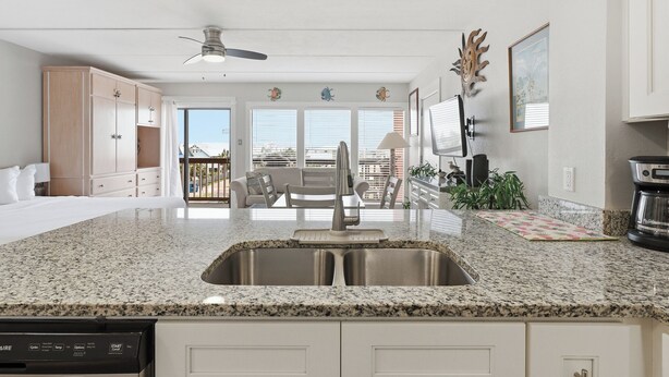 A modern kitchen with granite countertops, stainless steel appliances, and a view to the outside.