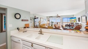 Una cocina con una isla grande, lavavajillas y un comedor con sillas y mesa.