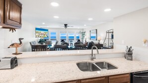 A kitchen with a large island, a double sink, and a dining area with a view.
