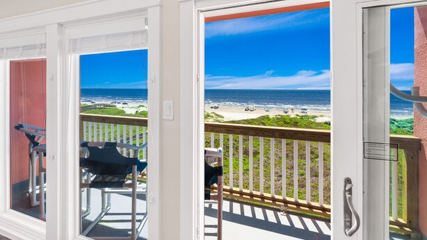 A balcony with a view of the beach and ocean.