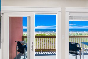 Un balcon avec vue sur la plage, une porte avec une serviette et une chaise.