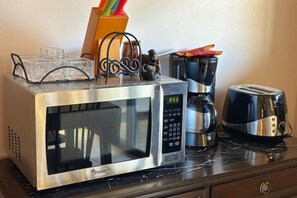 A microwave oven with a digital display, a toaster, and a coffee maker on a countertop.