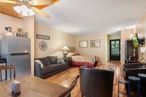 A compact living space with a kitchenette, a sofa, a dining table, and a TV.