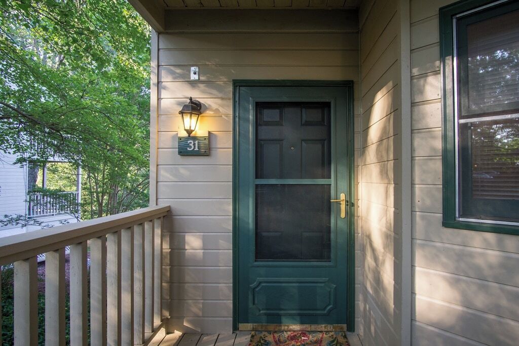 A house with a green door, a number '31' sign, and a porch with a railing.
