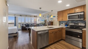 A modern kitchen with wooden cabinets, stainless steel appliances, and a large island with a sink. - Beachfront Boutique Resort | Pelican's Perch | Casa Condo 506 (Port Aransas)