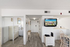 A hotel room with a bed, a dresser, a small table, a TV mounted on the wall, and a chair.