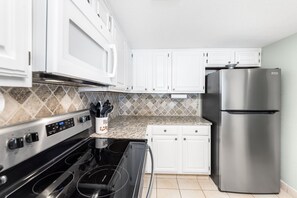 Kitchen features a granite countertop, stainless steel appliances, and a black stovetop with digital controls.
