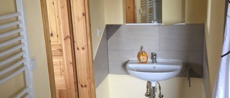 A bathroom with a wooden door, a white sink, a mirror, and a shower curtain.
