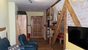 A living room with a TV, wooden furniture, and a brick wall. - Segelwohnung - Meerzauber. Gutshaus Reidervitz - Großer Lindengarten (Altenkirchen)