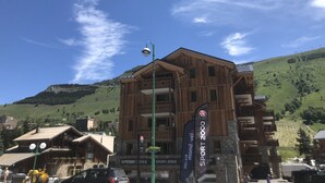 Ein Holzhaus mit Balkonen, einem Schild für 'Sport 2000' und einer Bergkulisse.
