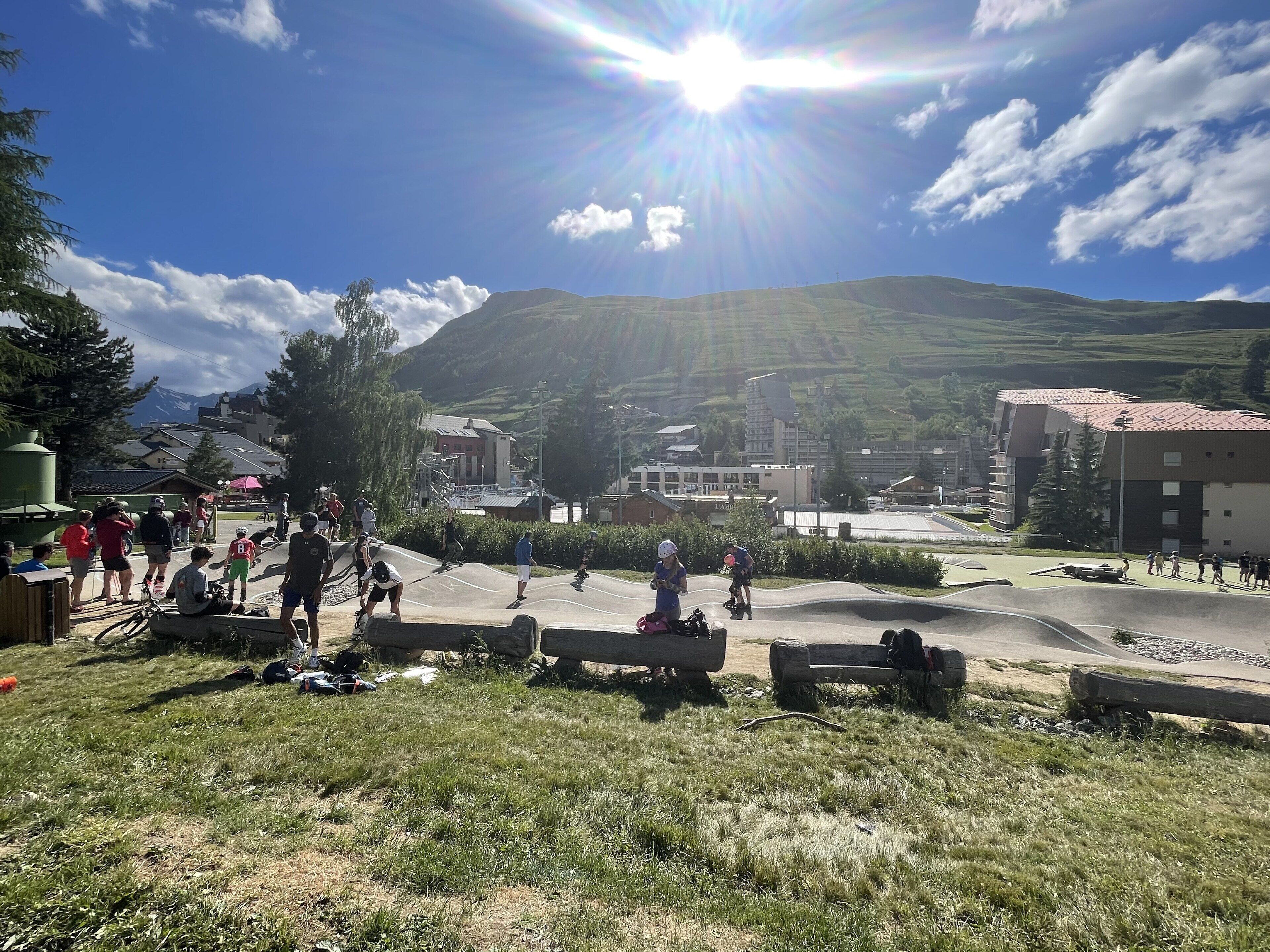 A sunny outdoor area with a skate park, benches, and a mountainous backdrop.