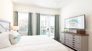 A bedroom with a large bed, a dresser, a TV, and a view of the outside. - Classic Margaritaville Cottage with Pool, Full Kitchen & Outdoor Living (Kissimmee)