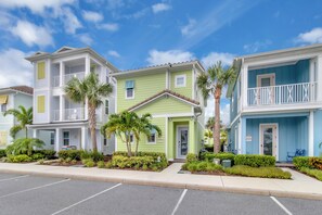 A row of three-story buildings with balconies, palm trees, and a clear blue sky. - Classic Margaritaville Cottage with Pool, Full Kitchen & Outdoor Living (Kissimmee)