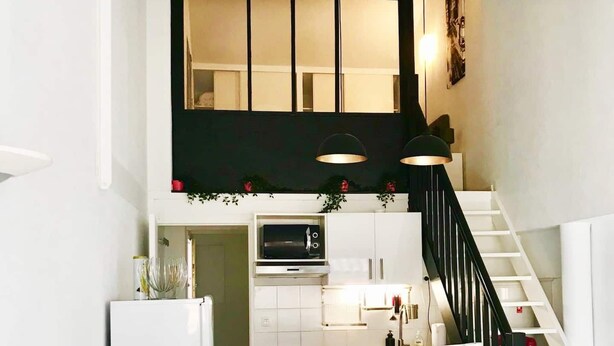 Eine moderne Küche mit weißen Schränken, einer Mikrowelle und einer Treppe, die in eine obere Etage führt.
