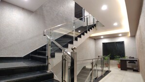 A modern staircase with glass railings and a metal handrail, leading to an upper floor. - Hotel Atul Residency (Satna)