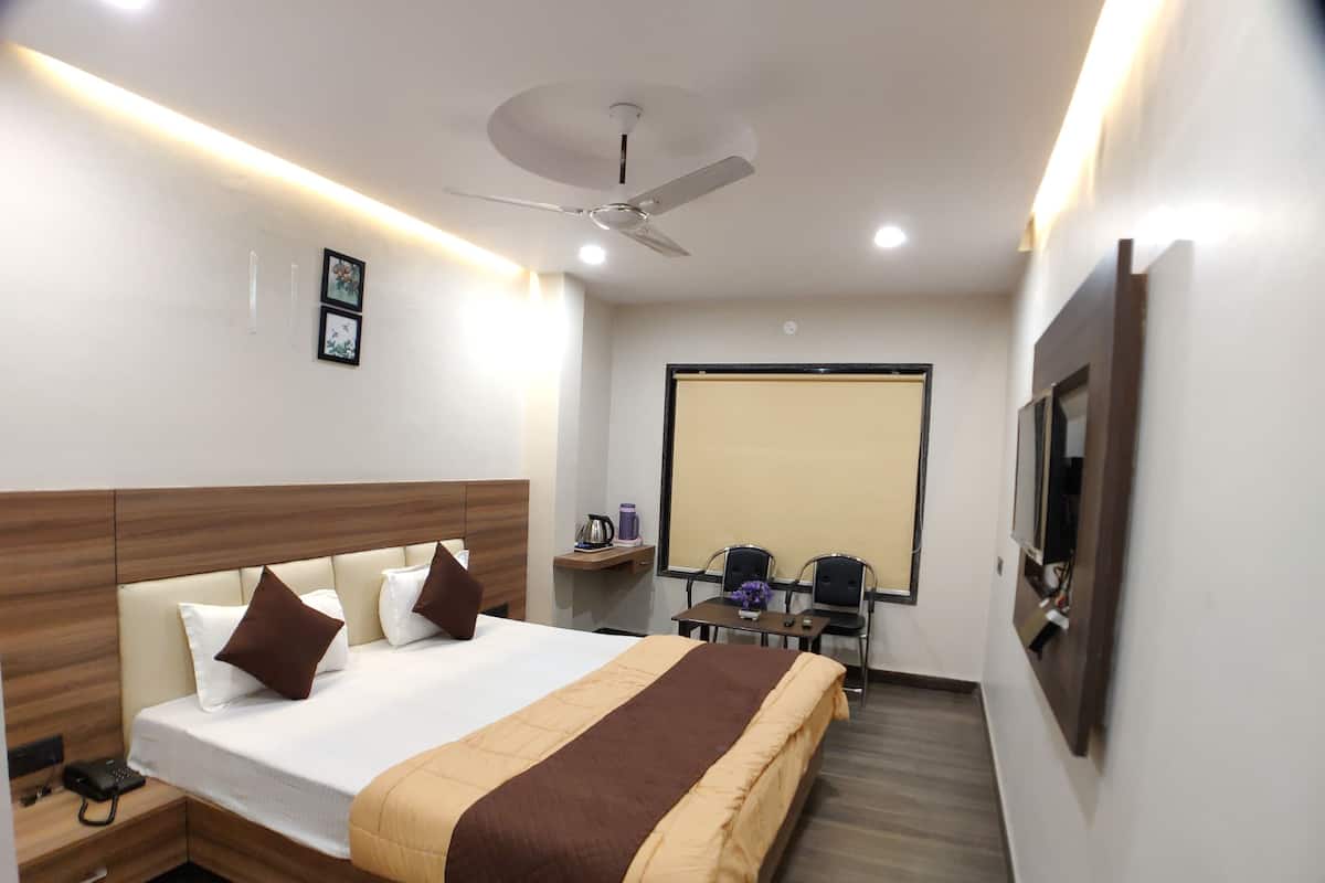 A hotel room with a bed, bedside table, lamp, and a ceiling fan.