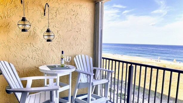 Ein Balkon mit Tisch und Stühlen mit Blick auf einen Strand.