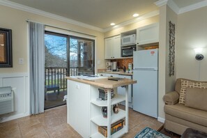 A compact kitchen with a central island, a microwave, and a refrigerator.