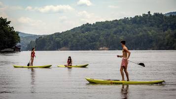 Three individuals on paddleboards in a calm body of water with a forested hillside in the background.