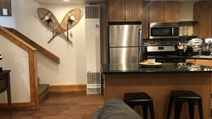 A modern kitchen with wooden cabinets, stainless steel appliances, and a central island with stools.