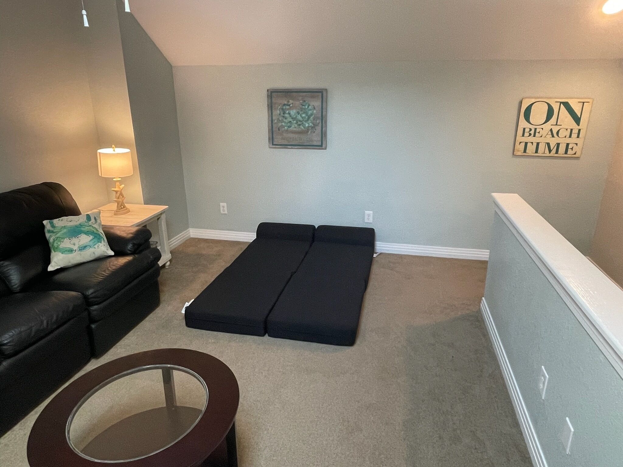 A living room with a black leather sofa, a small round table, and a black bench.