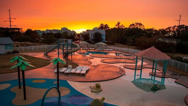 Un parque infantil con toboganes, una zona de juegos acuáticos y un pabellón.