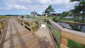 Un muelle de madera que conduce a una casa con un embarcadero, rodeado de agua y vegetación.