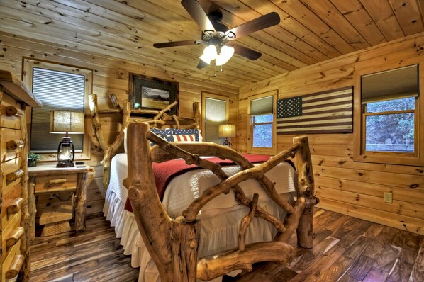 A log cabin bedroom with a bed, desk, and American flag. - Mountain Dream Hideaway | Stylish Cabin w/ Mountain Views, Hot Tub & Game Room (Blue Ridge)