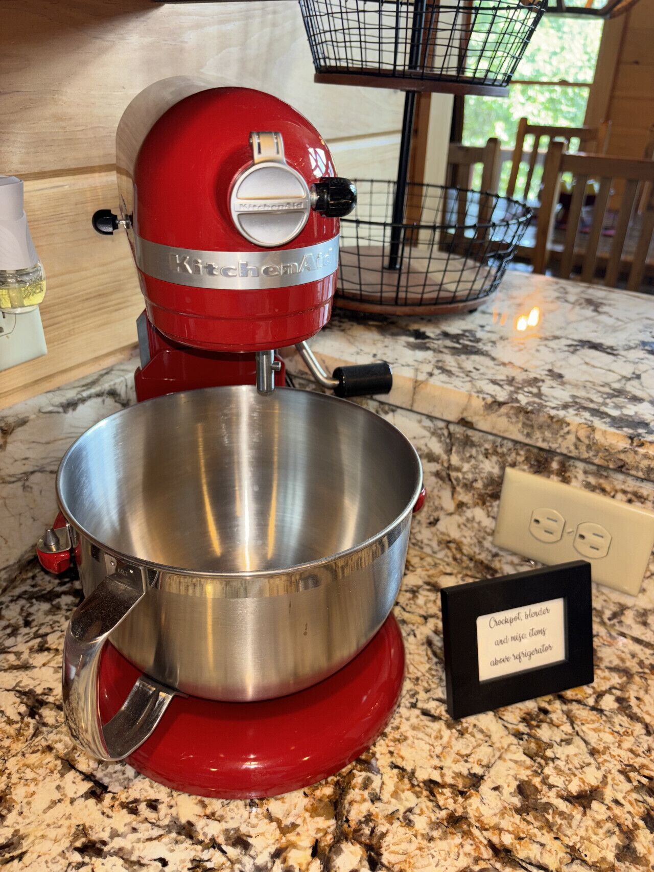 A red KitchenAid mixer with a stainless steel bowl on a granite countertop.