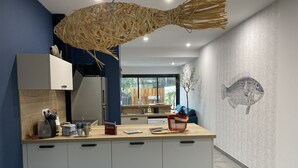 Una cuina moderna amb una illa de fusta, una taula de dinar i un mural decoratiu amb motius de peixos a la paret.
