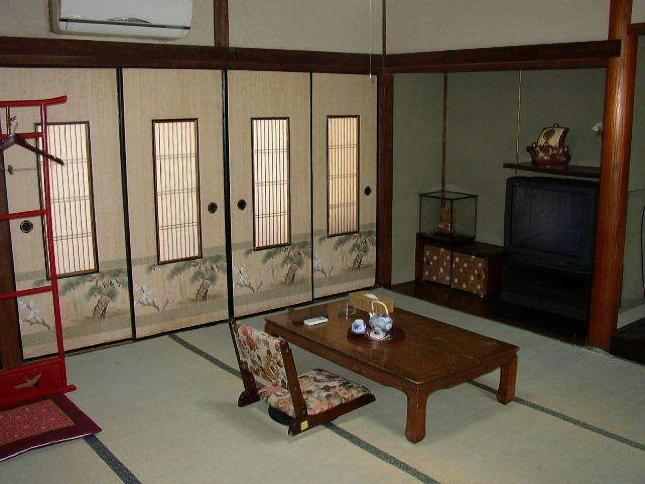 A traditional Japanese room with sliding doors, a television, a wooden table, and a chair.