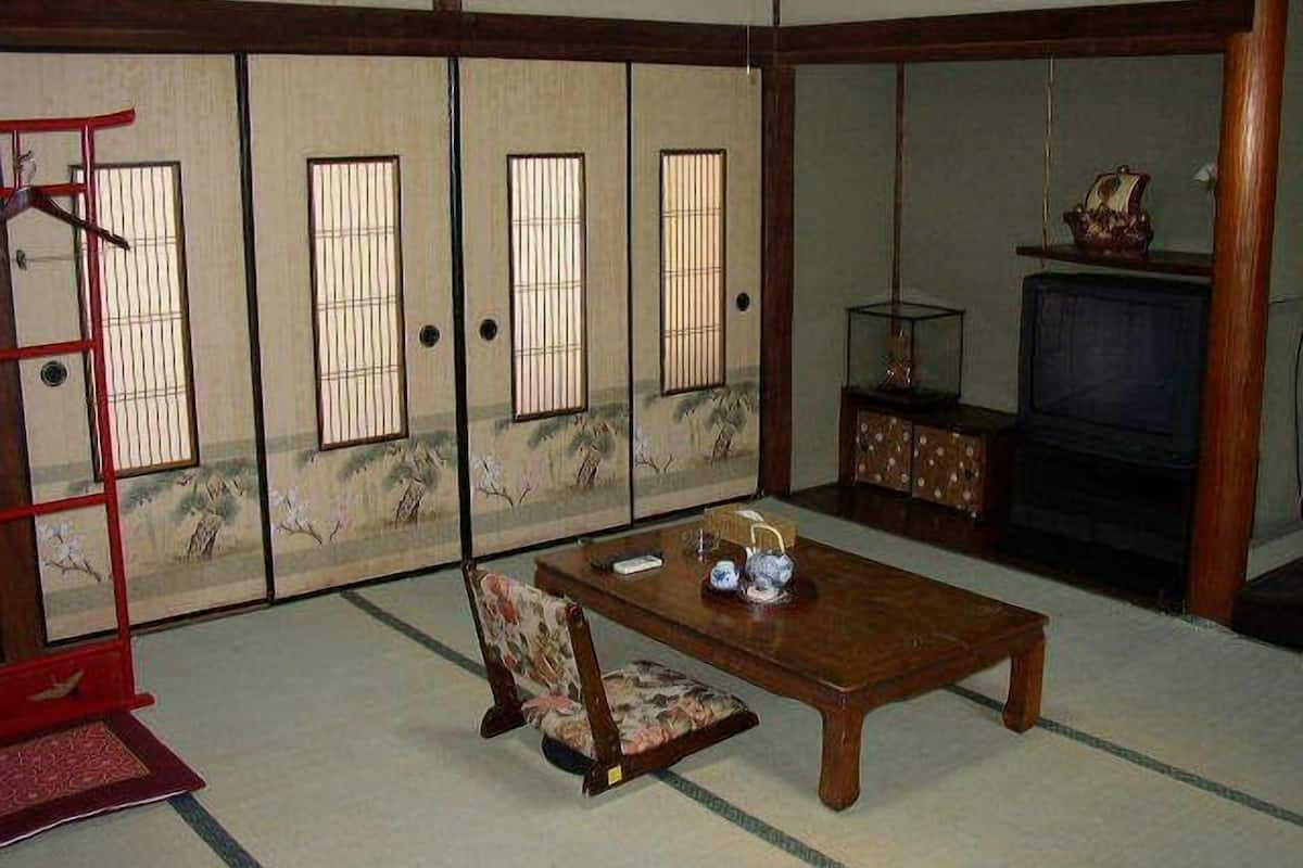 A traditional Japanese room with sliding doors, a television, a wooden table, and a chair.
