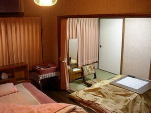 A traditional Japanese-style room with a bed, a desk, a chair, a small table, and a sliding door. - Yamane Ryokan (Mihara)