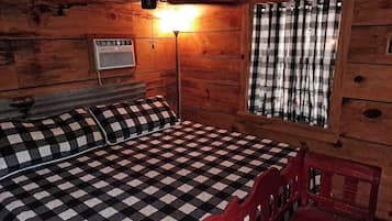 A room with a checkered bedspread, a red chair, a wall-mounted heater, and a window with checkered curtains.