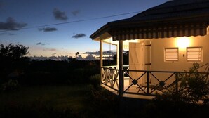 Een huis met een overdekte veranda en uitzicht op het landschap.