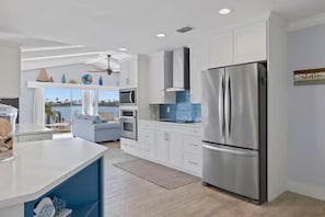 A modern kitchen with white cabinets, a stainless steel refrigerator, and a view of the ocean. - Villa Margarita - 4 Bedroom w/ Beautiful Lake View and Gulf Access! (Cape Coral)