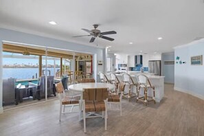 A spacious room with a round dining table, wicker chairs, a ceiling fan, and a view of the ocean. - Villa Margarita - 4 Bedroom w/ Beautiful Lake View and Gulf Access! (Cape Coral)